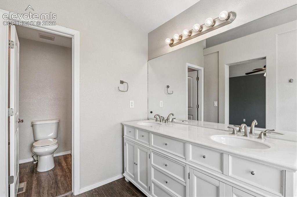 Image 21 of 46: Primary bathroom features dual vanity with marble countertop and private wa