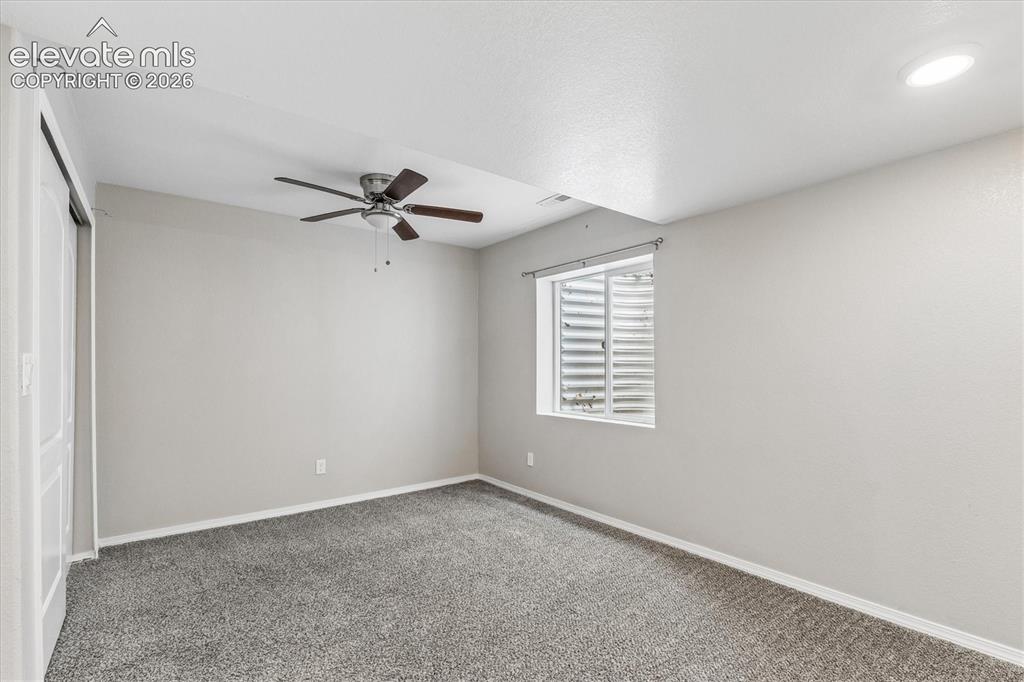 Image 39 of 46: Spacious basement bedroom with ceiling fan and overhead lighting