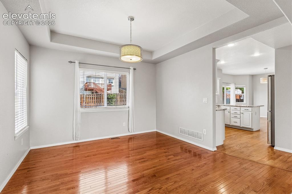 Image 8 of 46: Formal dining room with wood floors and tray ceiling detail