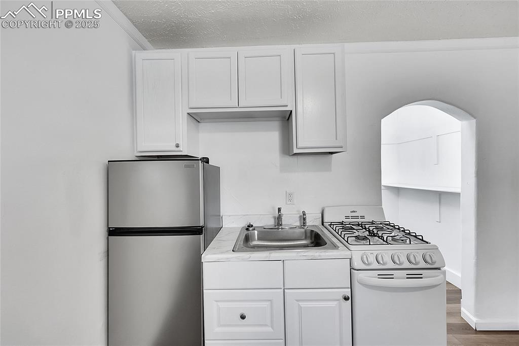 Image 10 of 32: Kitchen with freestanding refrigerator, white range with gas stovetop, wood