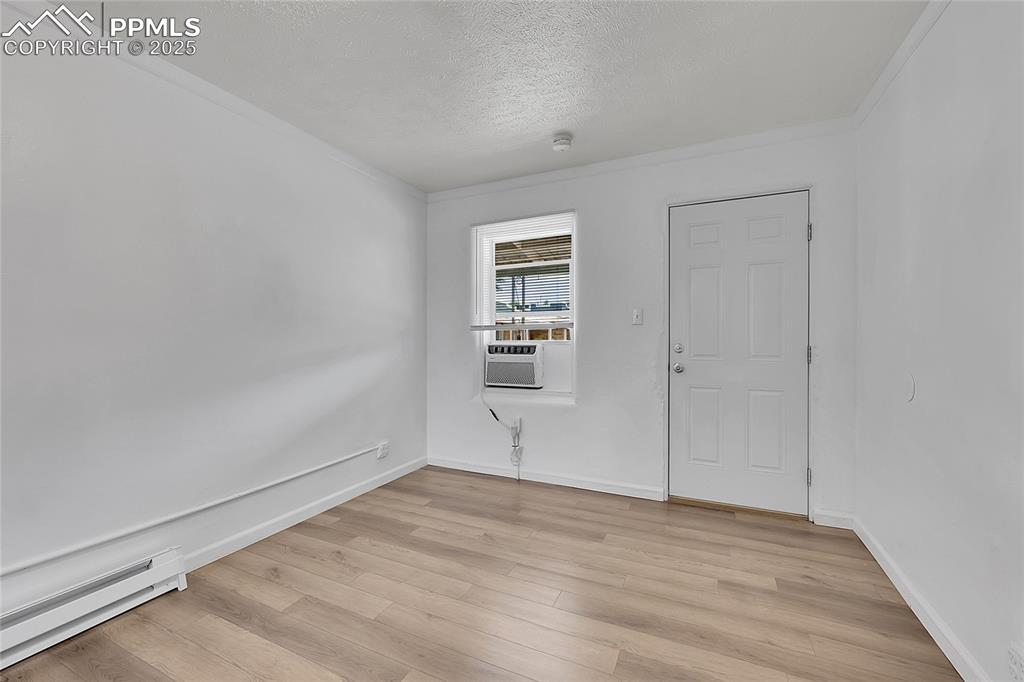 Image 11 of 32: Spare room featuring baseboard heating, light wood-style floors, a textured