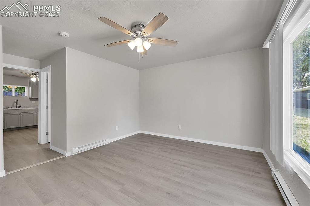 Image 13 of 32: Empty room featuring a ceiling fan, baseboard heating, a smoke detector, an
