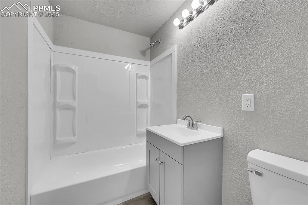 Image 14 of 32: Full bath with a textured wall, vanity, shower / tub combination, and a tex
