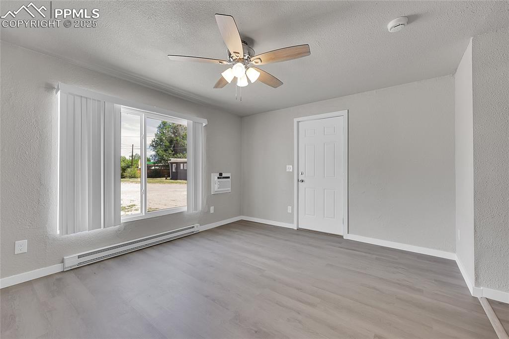 Image 15 of 32: Unfurnished room featuring a baseboard radiator, a smoke detector, wood fin