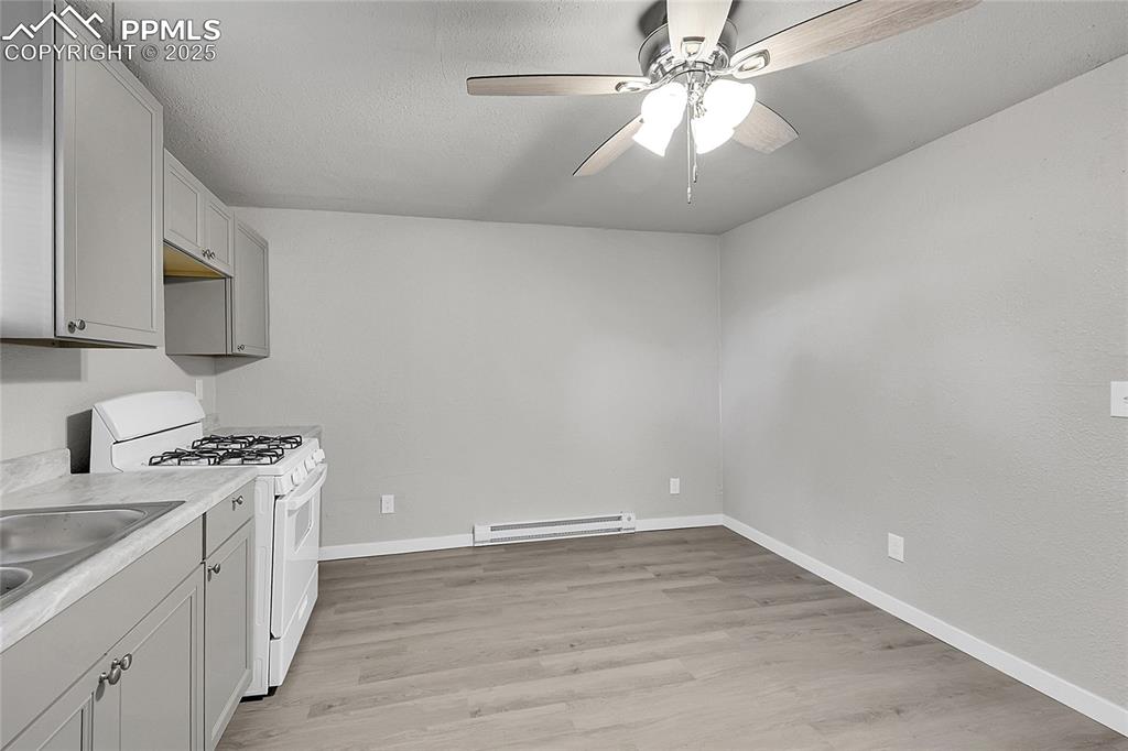 Image 17 of 32: Kitchen featuring white range with gas stovetop, a baseboard heating unit, 