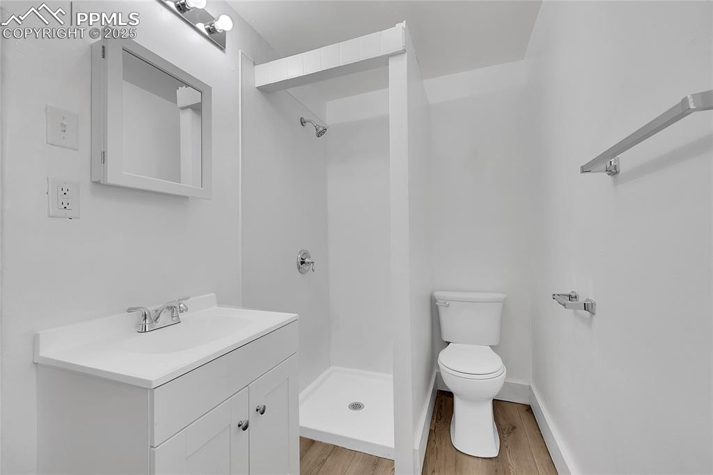Image 18 of 32: Full bath featuring a shower stall, wood finished floors, and vanity