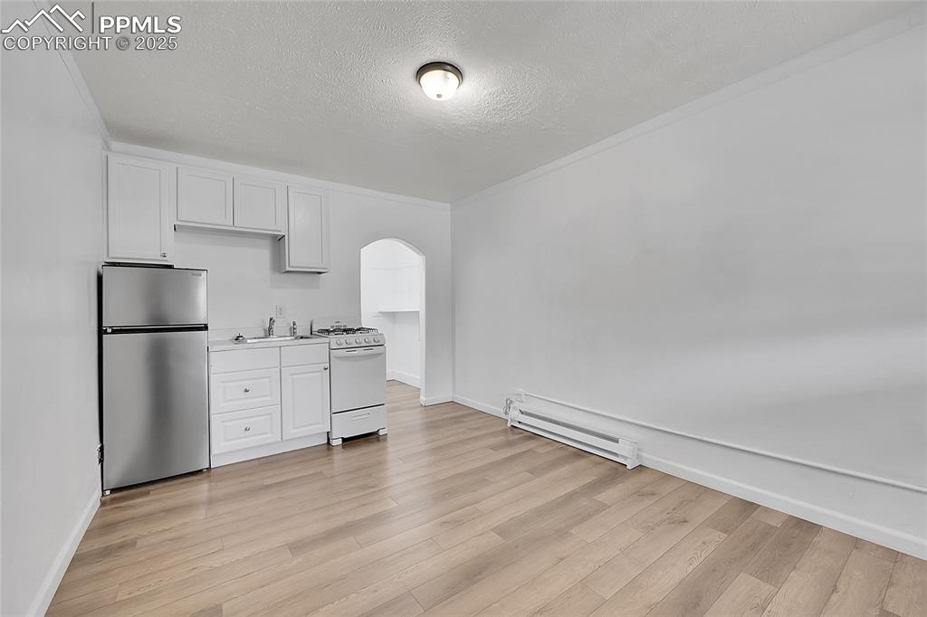 Image 19 of 32: Kitchen featuring freestanding refrigerator, white gas range, a baseboard r