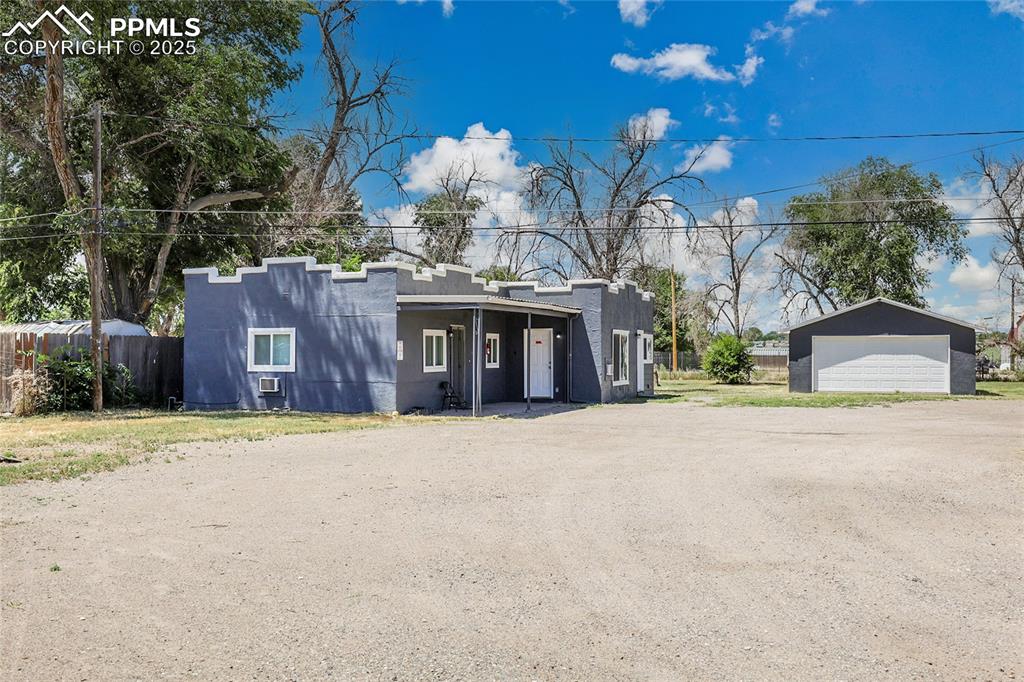Image 3 of 32: View of front facade featuring stucco siding, a detached garage, and an out