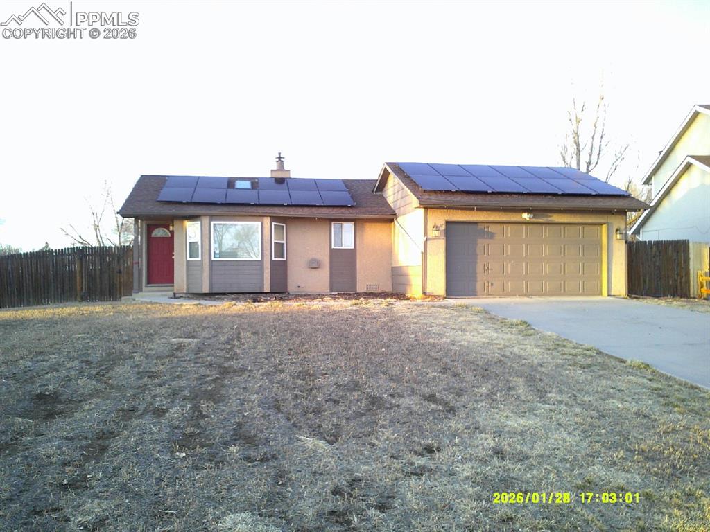 Caption: View of front of property featuring roof mounted solar panels, concrete driveway, a garage, and stuc