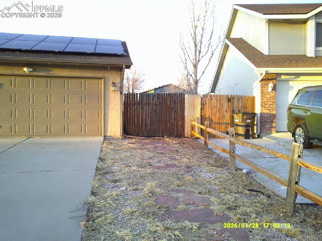 Image 2 of 22: View of side of property with solar panels, a garage, brick siding, and con
