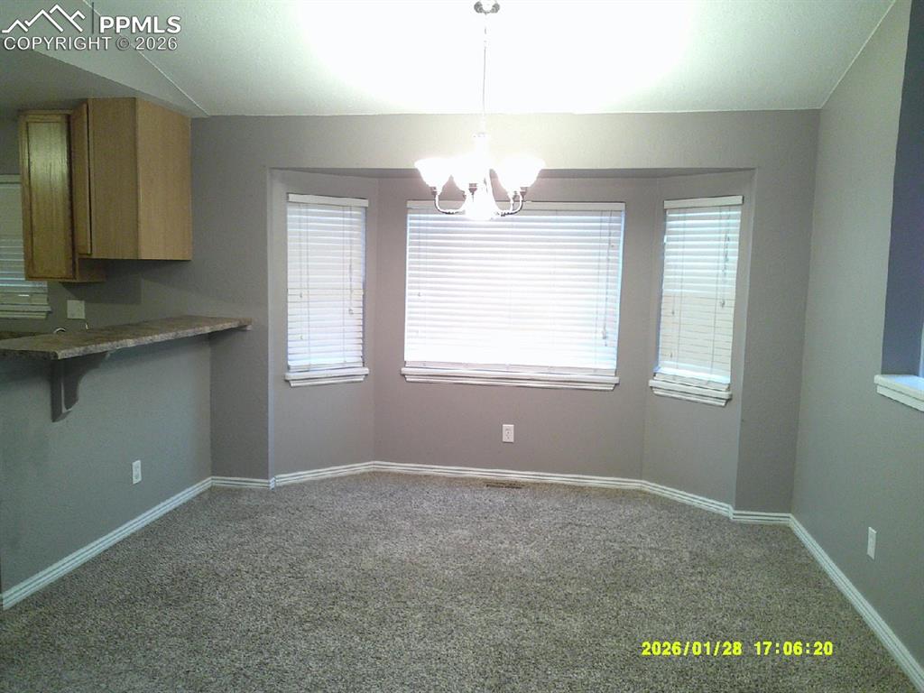 Image 9 of 22: Unfurnished dining area with dark carpet and hanging lights