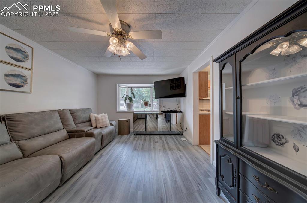 Image 14 of 32: Family room with bay window, wood style floors, and a ceiling fan