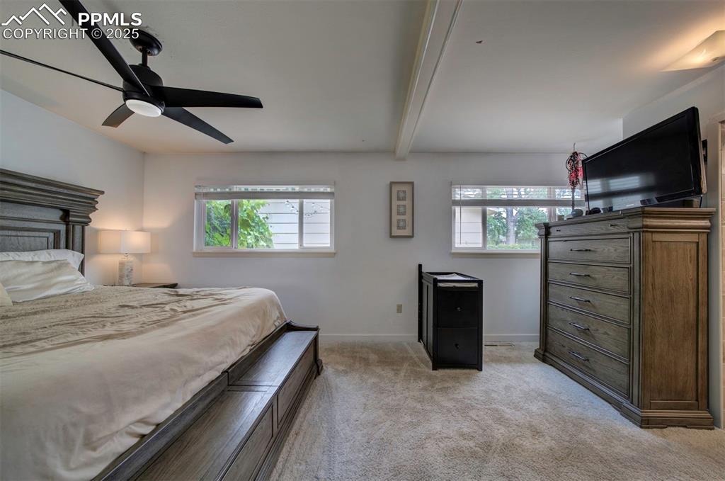 Image 17 of 32: Bedroom with beam ceiling, light carpet, and a ceiling fan