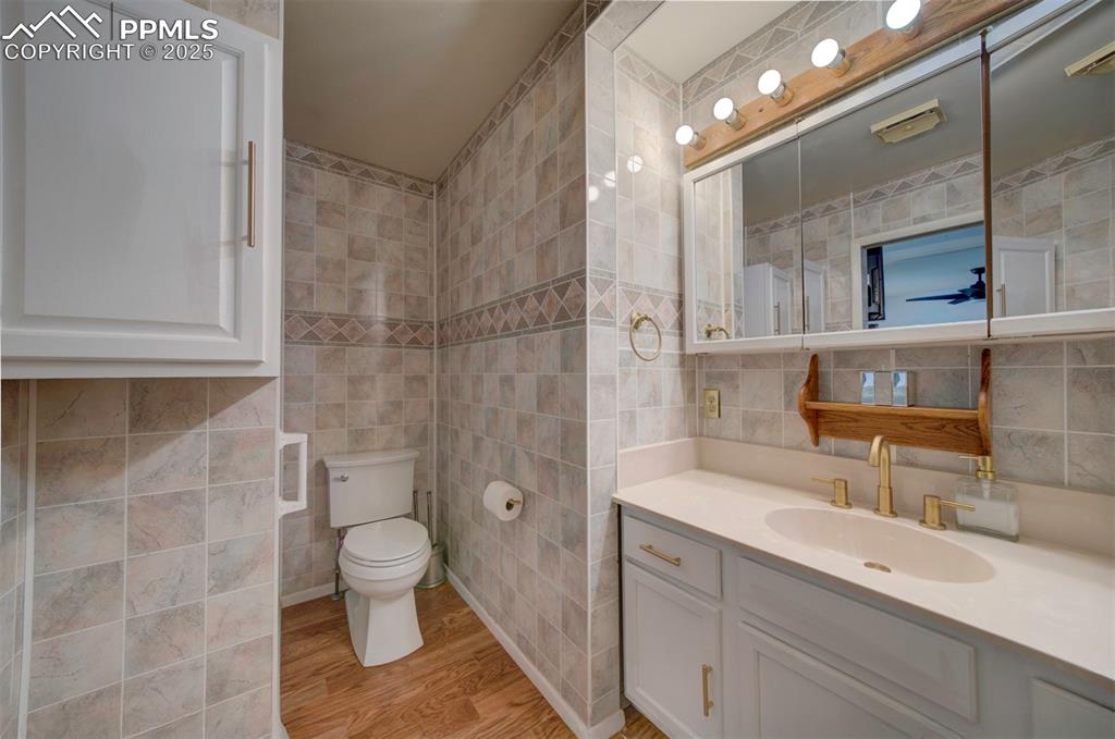 Image 20 of 32: Bathroom featuring wood finished floors, vanity, and tile walls