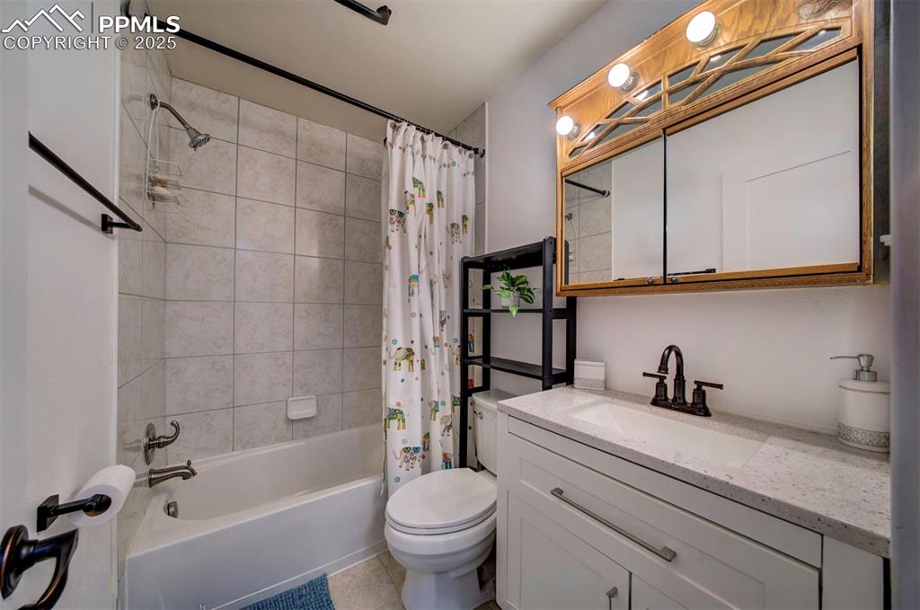 Image 21 of 32: Bathroom featuring vanity, shower / bath combo with shower curtain, and til
