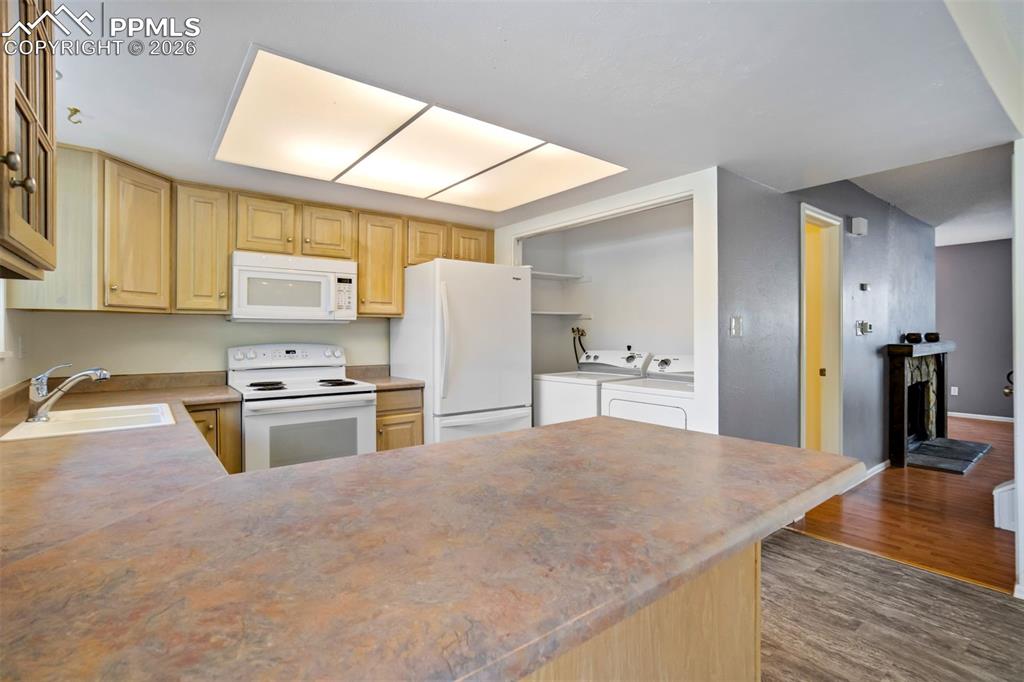 Image 12 of 49: Kitchen featuring wood cabinetry, white appliances, a built-in microwave, a
