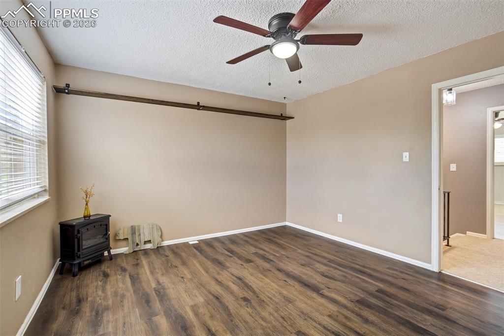 Image 15 of 49: Spacious room featuring wood-finish flooring, a ceiling fan with integrated