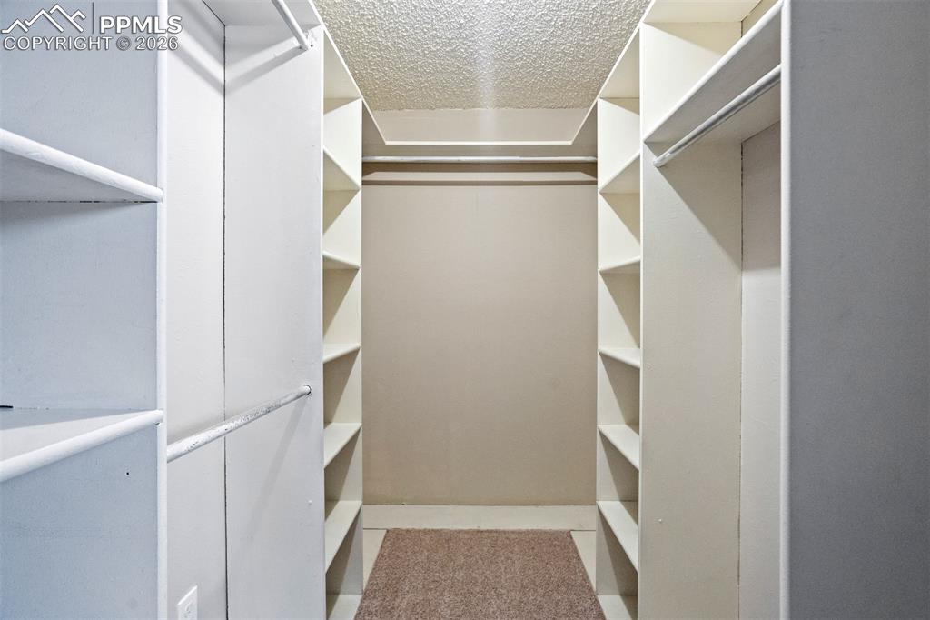 Image 20 of 49: Walk-in closet featuring extensive built-in shelving, multiple hanging rods