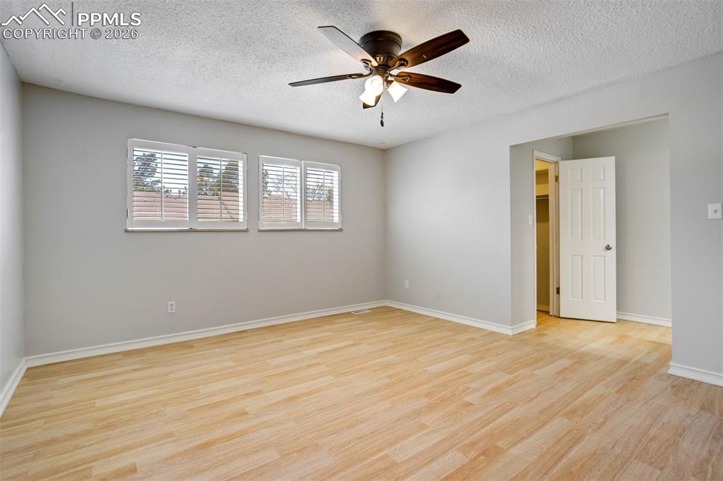 Image 21 of 49: Spacious room featuring light wood-finish flooring, three windows with whit