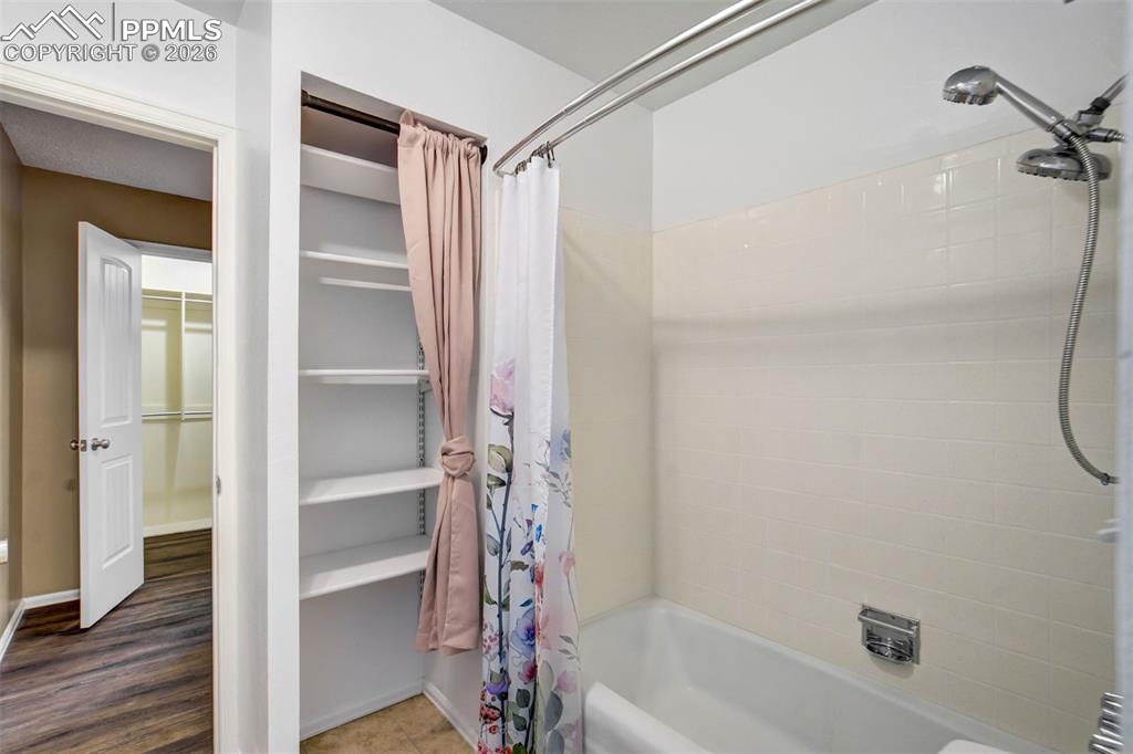 Image 24 of 49: Bathtub with tiled surround and adjustable showerhead