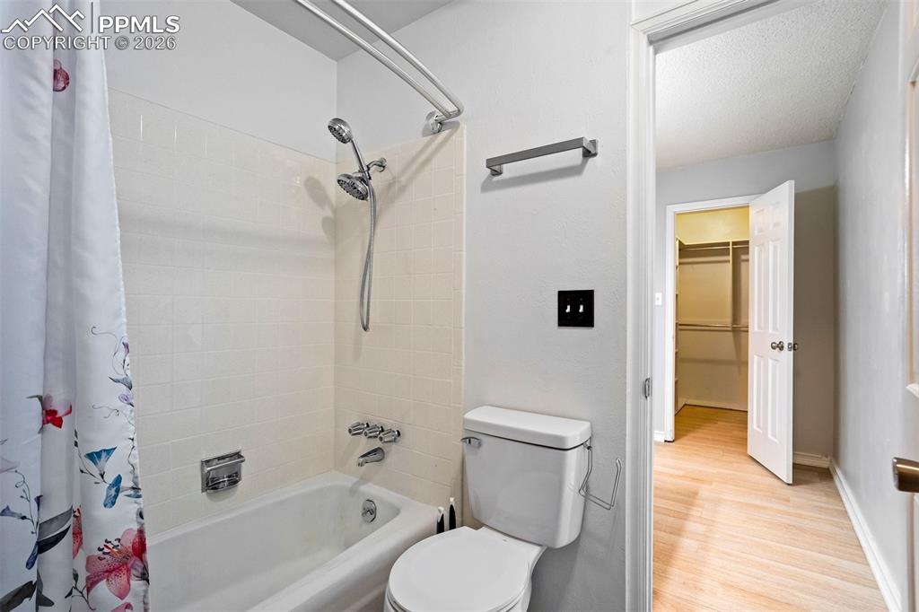 Image 25 of 49: White bathroom featuring a bathtub with a tiled surround, a toilet, a chrom