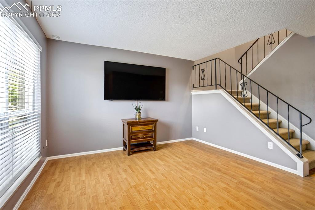 Image 3 of 49: Spacious room featuring wood-finish flooring, a wall-mounted television, an