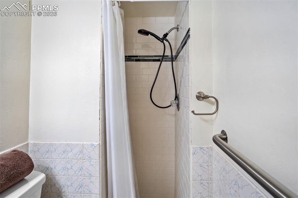 Image 33 of 49: Walk-in shower with subway tile surround and black accent tile