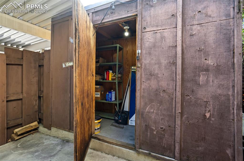 Image 39 of 49: Utility shed with wood-paneled walls and a concrete floor