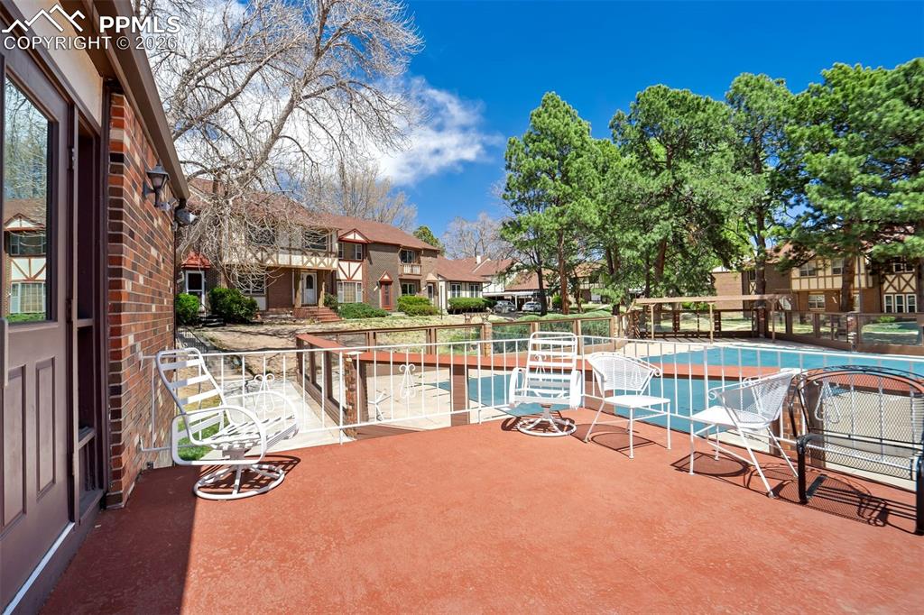 Image 41 of 49: Expansive patio with terracotta-hued flooring, white metal railings, and di
