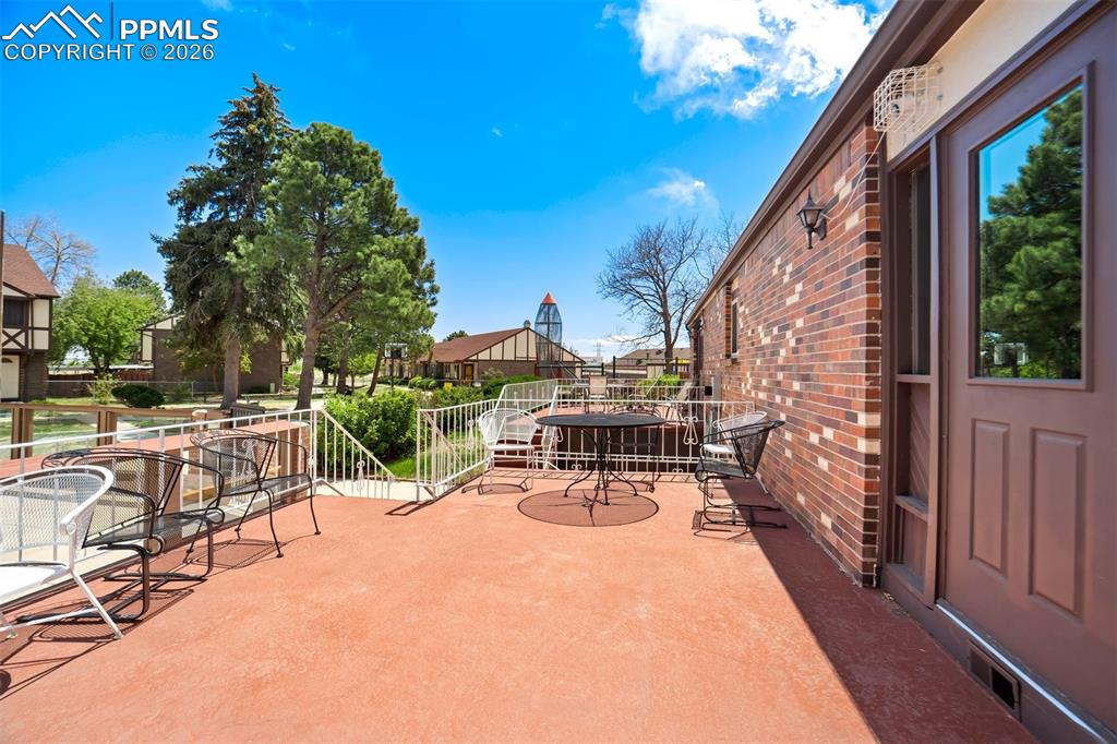 Image 42 of 49: Spacious outdoor patio with a textured concrete surface, white metal railin