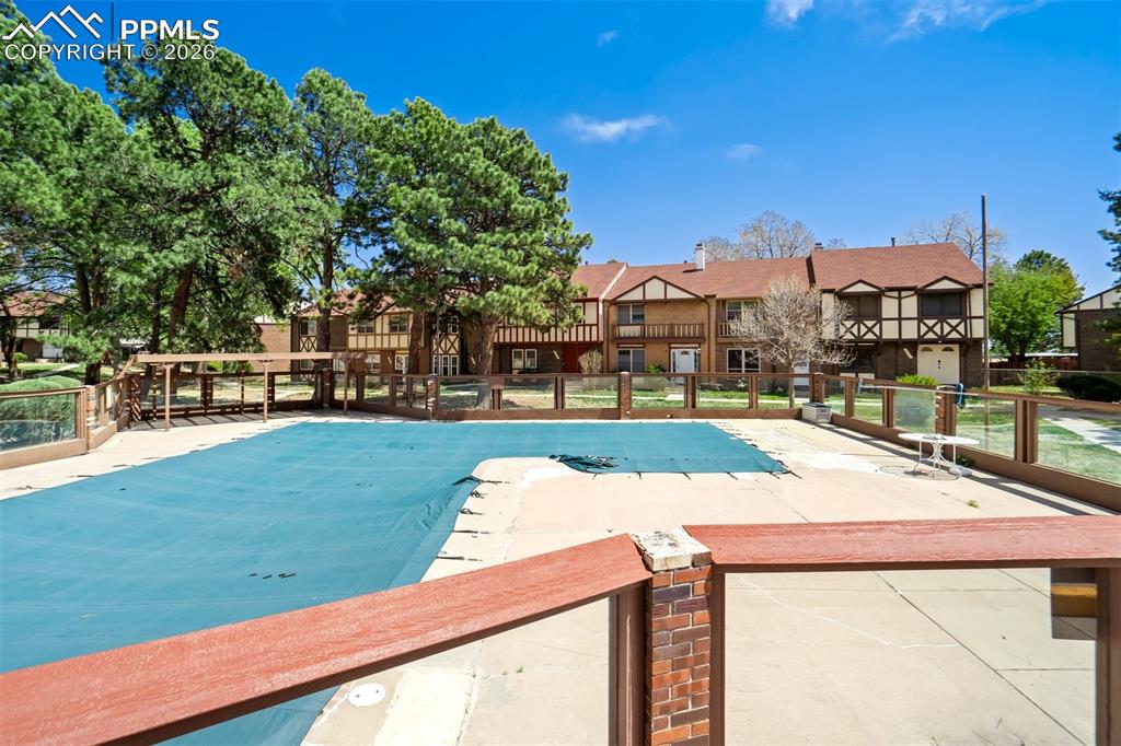 Image 43 of 49: Outdoor swimming pool with a blue cover, surrounded by a concrete deck and 