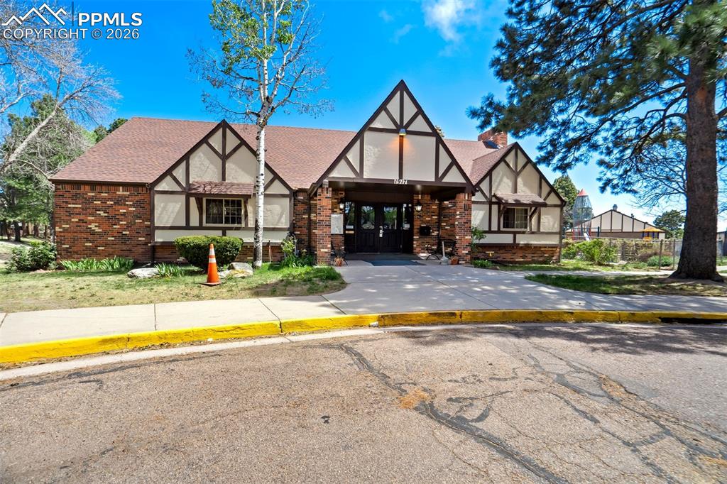 Image 44 of 49: Tudor-style building featuring brick and stucco siding with dark wood trim,
