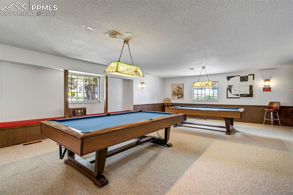 Image 47 of 49: Spacious recreation room featuring two full-size billiard tables, carpeted 
