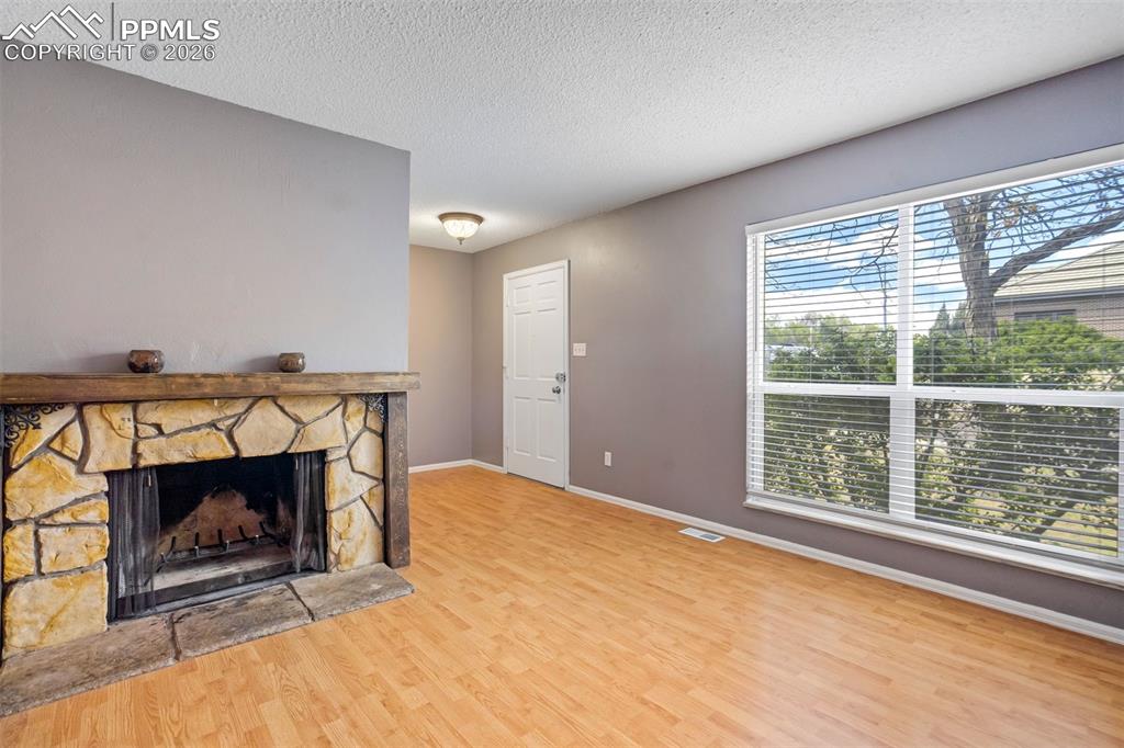 Image 5 of 49: Room featuring a stone fireplace with a wood mantel, wood-finish flooring, 