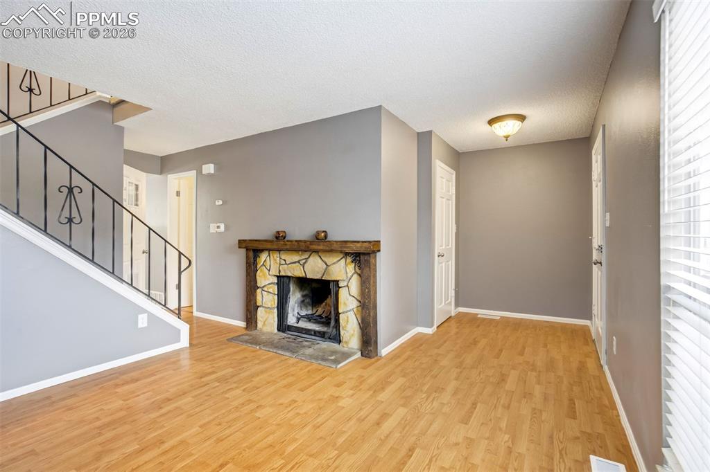 Image 6 of 49: Living area featuring wood-finish flooring, a stone-surround fireplace with