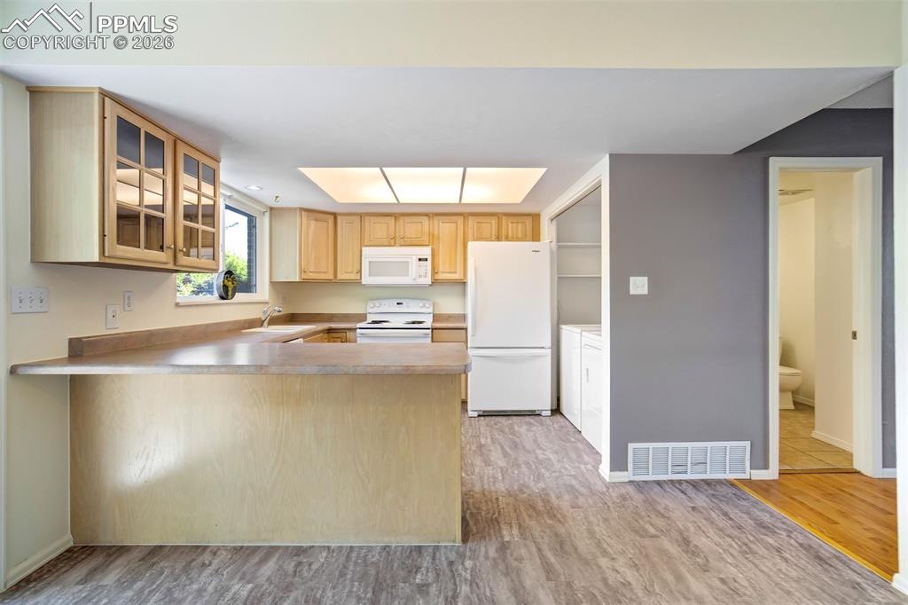 Image 8 of 49: Open-concept kitchen featuring wood-finish flooring, light wood cabinetry w