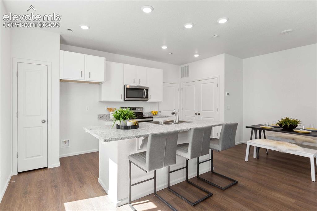 Image 13 of 30: Kitchen featuring white cabinetry, stainless steel microwave, and a center