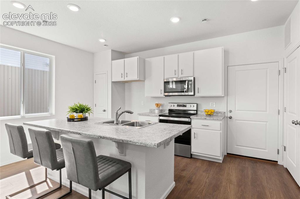 Image 14 of 30: Kitchen featuring white cabinetry, stainless steel appliances, a double bas