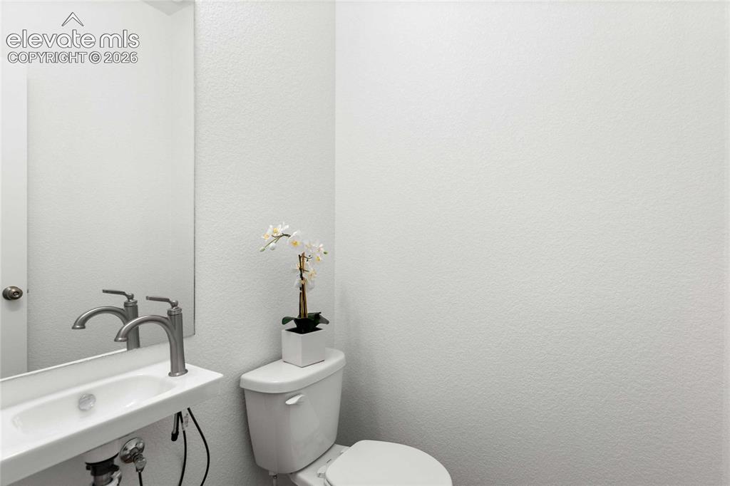 Image 16 of 30: Wall-mounted sink with a modern brushed nickel faucet and a frameless mirro