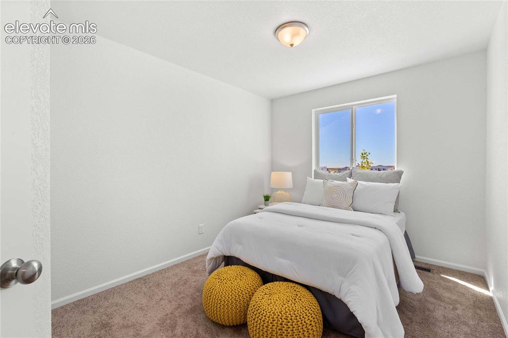 Image 26 of 30: Bright secondary bedroom featuring large windows with natural light, neutra