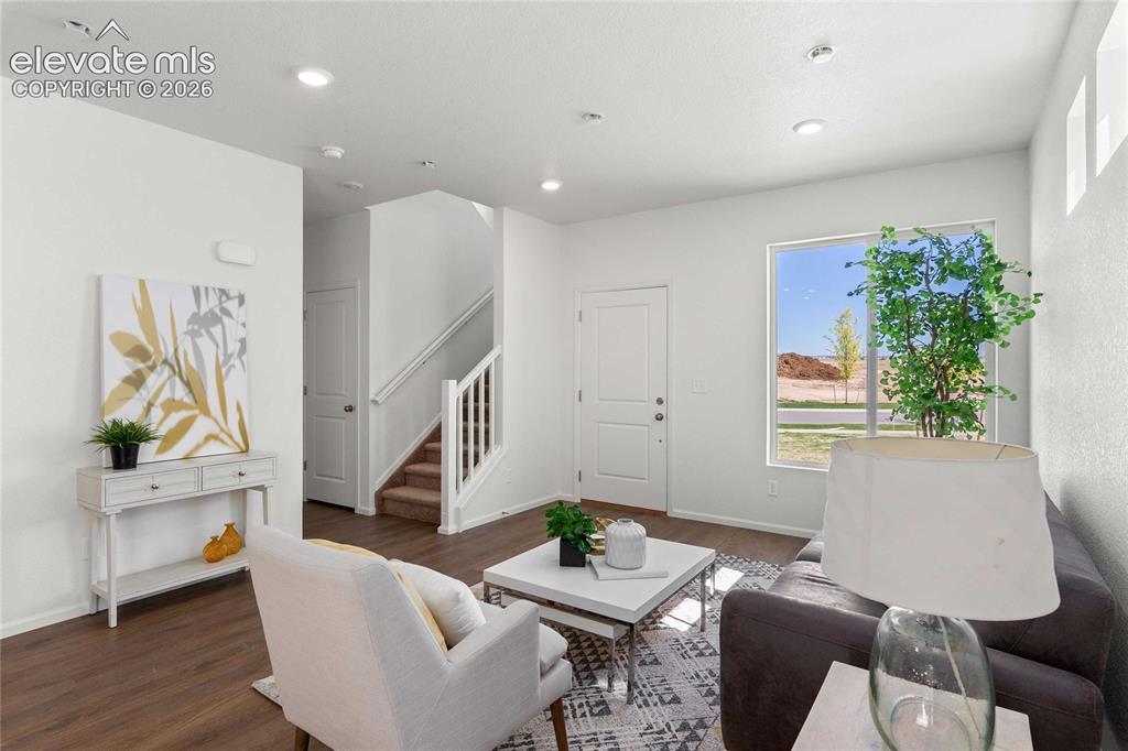 Image 9 of 30: Open-concept living area with wood-finish flooring, recessed lighting, and 