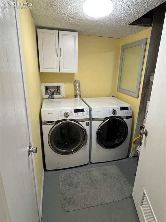 Image 20 of 40: Laundry room featuring a textured ceiling, cabinet space, and independent w