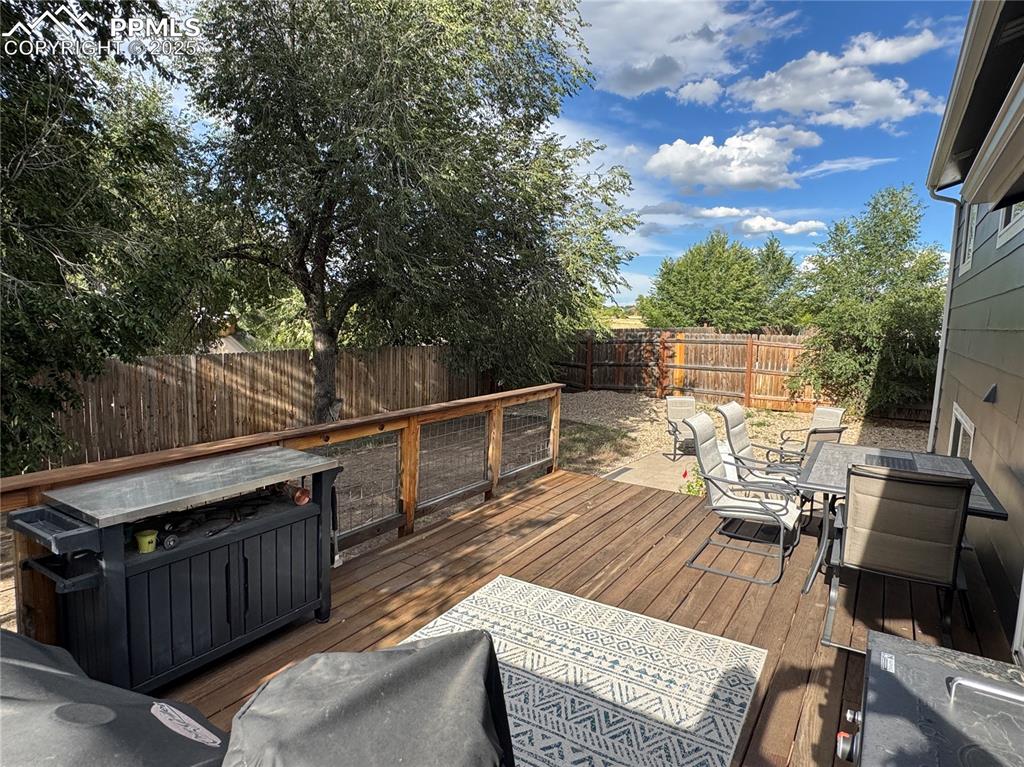 Image 24 of 40: Wooden terrace with outdoor dining area and a fenced backyard