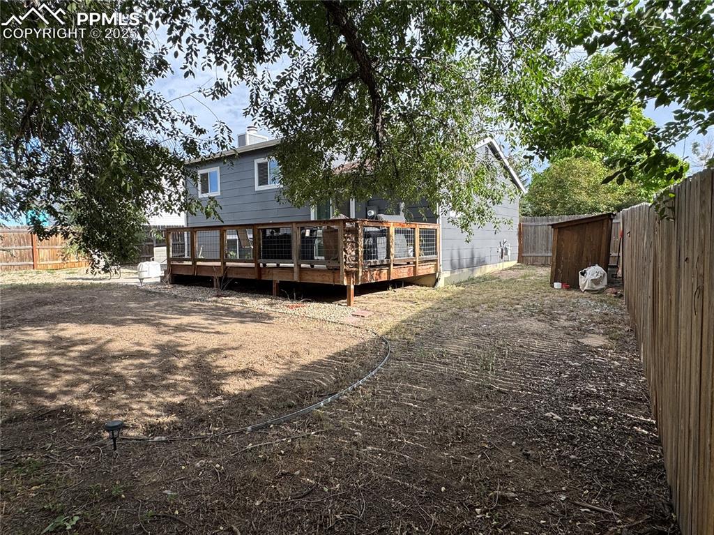 Image 29 of 40: Rear view of property with a fenced backyard, a deck, and a chimney