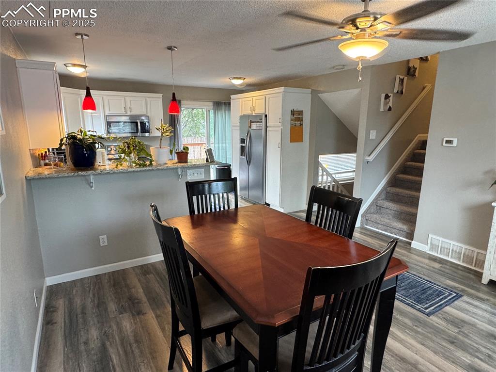 Image 5 of 40: Dining space with a textured ceiling, stairs, dark wood-type flooring, and