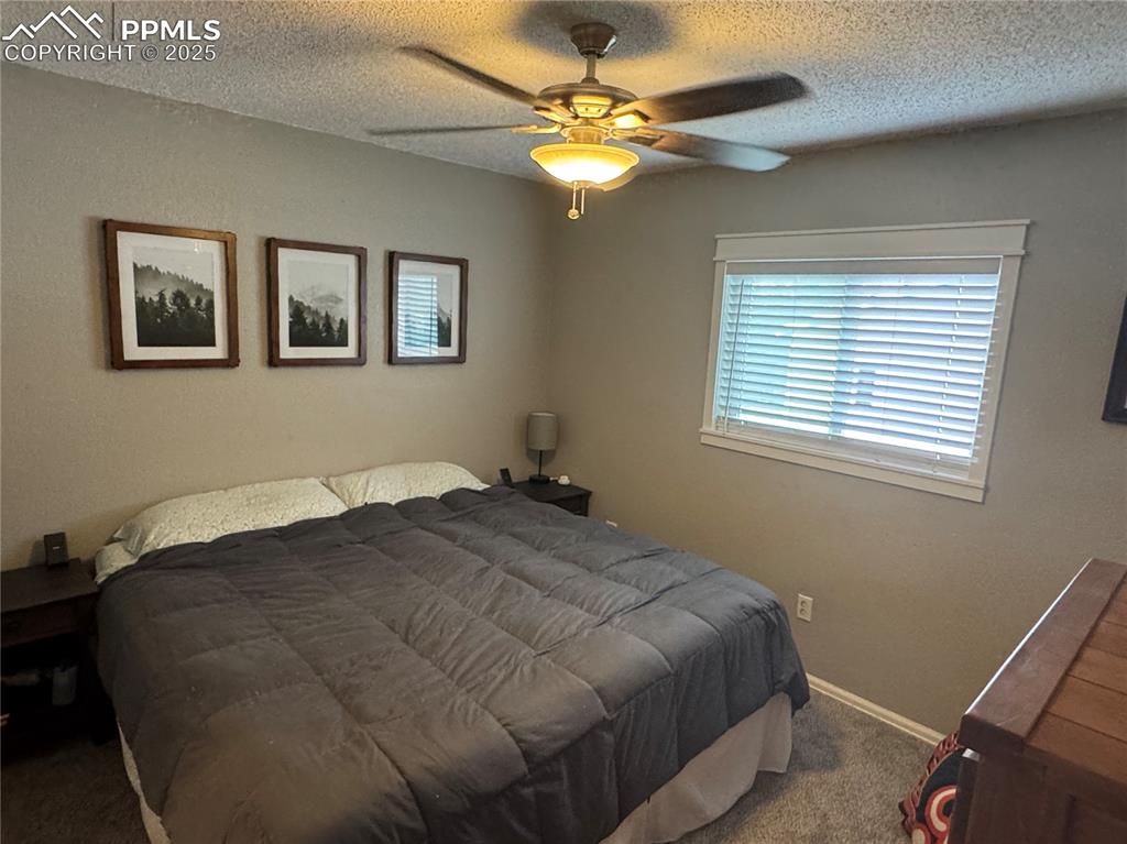 Image 9 of 40: Bedroom featuring carpet floors, a textured ceiling, and ceiling fan