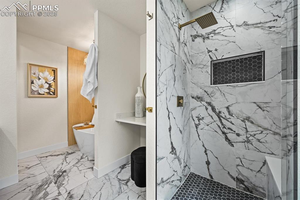 Image 19 of 47: Full bathroom featuring a freestanding bath, a marble finish shower, and li
