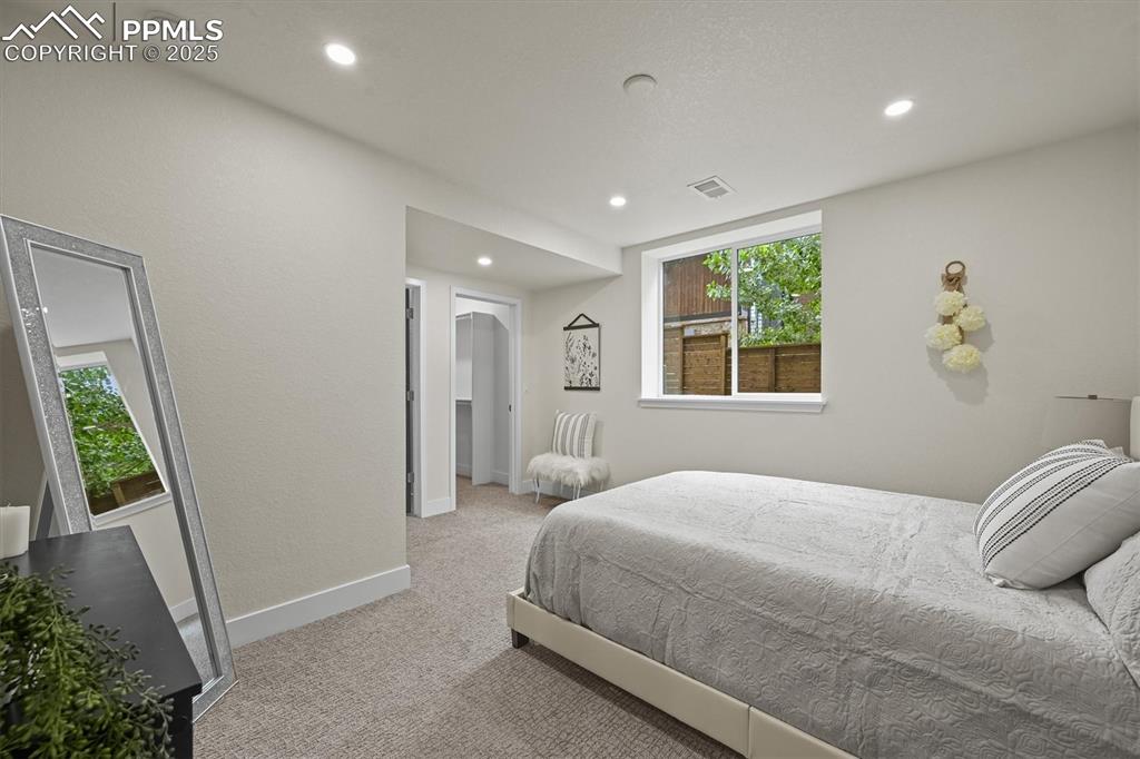 Image 21 of 47: Bedroom with multiple windows, light carpet, recessed lighting, and arched 