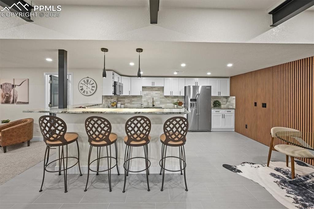 Image 26 of 47: Kitchen with light stone counters, white cabinetry, tasteful backsplash, ap