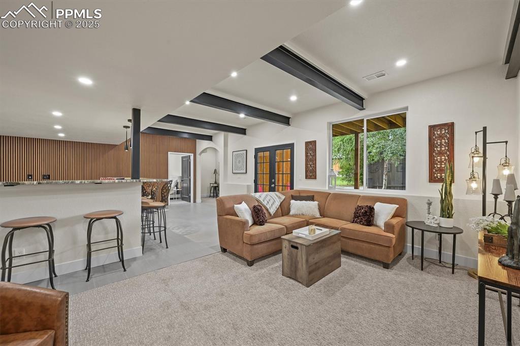 Image 28 of 47: Living area with beamed ceiling, wooden walls, arched walkways, and recesse